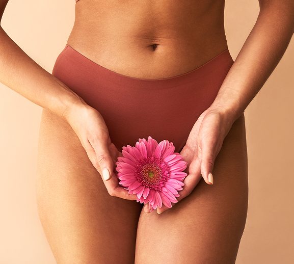 Woman holding a flower in front of her underwear