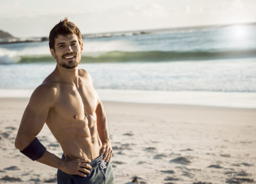 smiling fit man relaxing after workout on beach